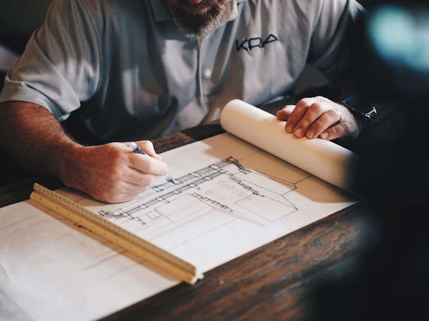 Concepteur traçant des plans à la règle sur un plan de travail