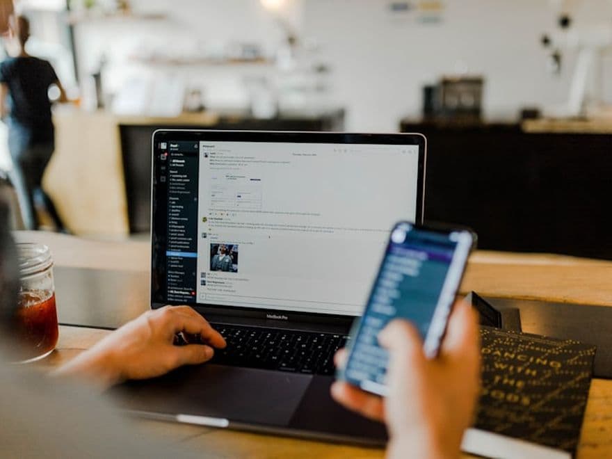 Personne préparant ses publications sur un ordinateur et un téléphone